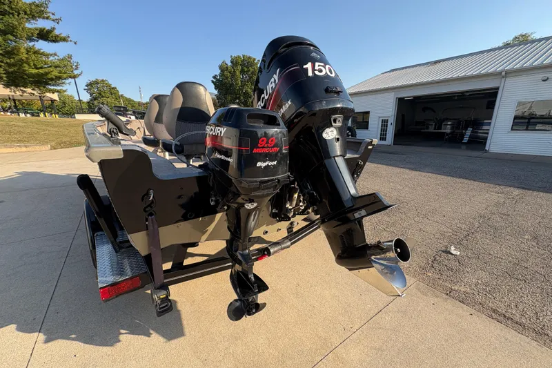 Slide: The Image of 2004 Lund 1800 Explorer SS boat with Mercury outboard motor, parked near a building. - 27