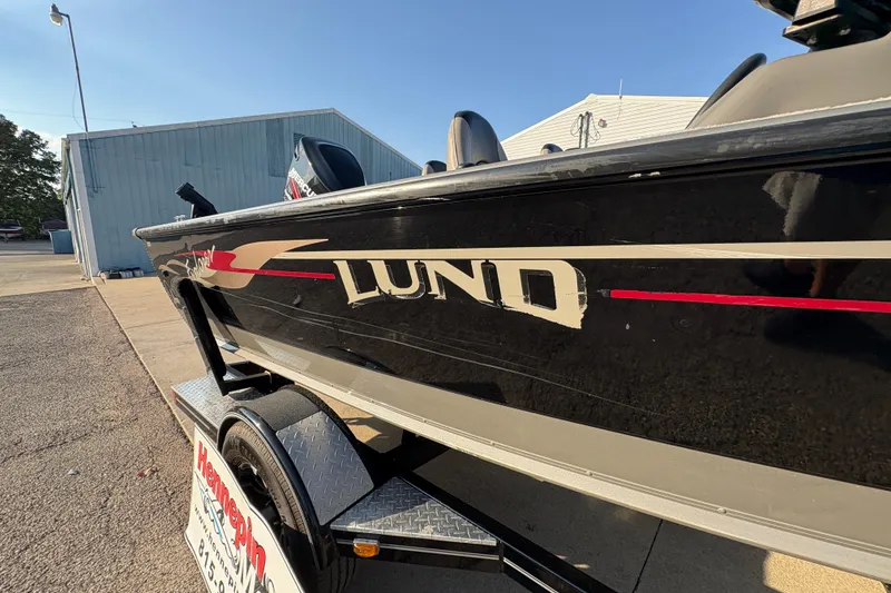Slide: The Image of 2004 Lund 1800 Explorer SS boat on trailer, black with red accents, parked outdoors. - 32