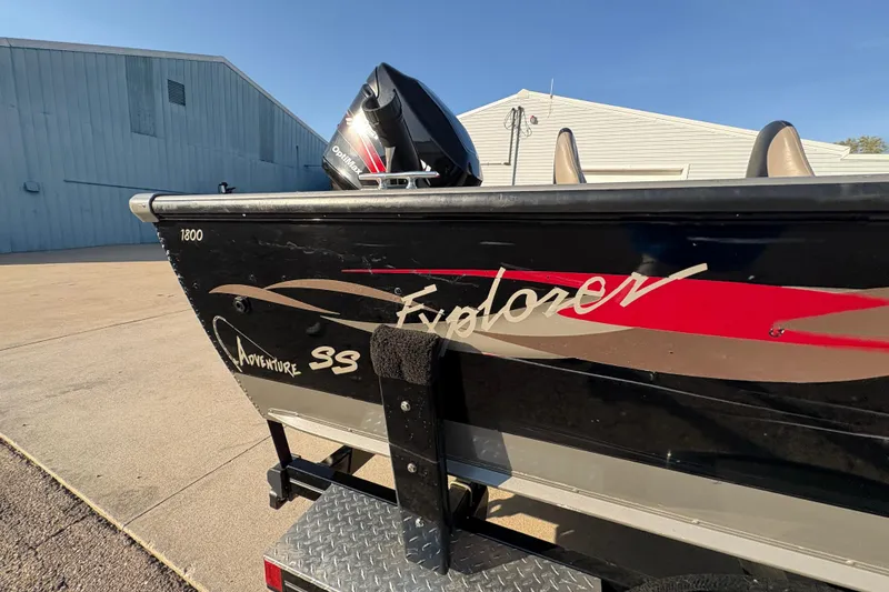 Slide: The Image of 2004 Lund 1800 Explorer SS boat with outboard motor, parked near a building. - 33