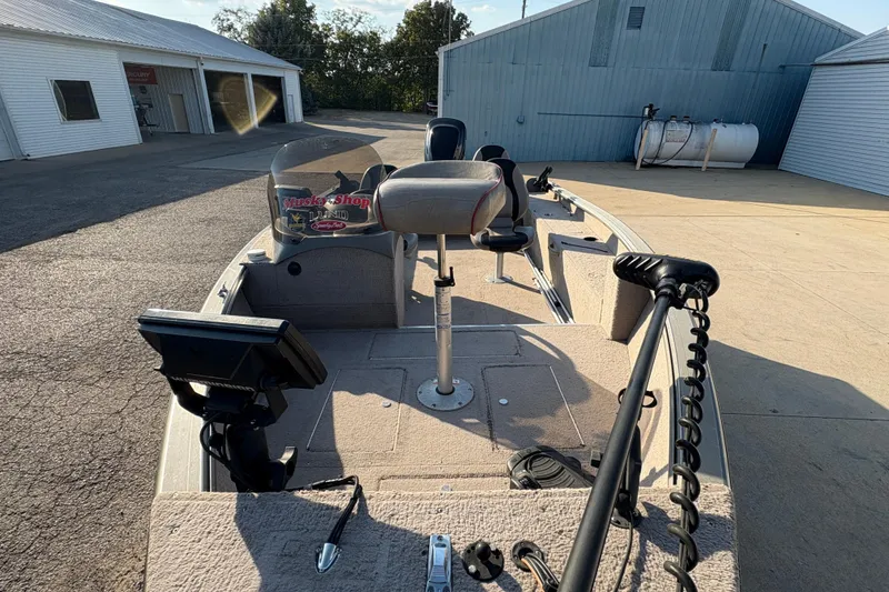 Slide: The Image of 2004 Lund 1800 Explorer SS boat with fishing equipment, parked near industrial buildings. - 8