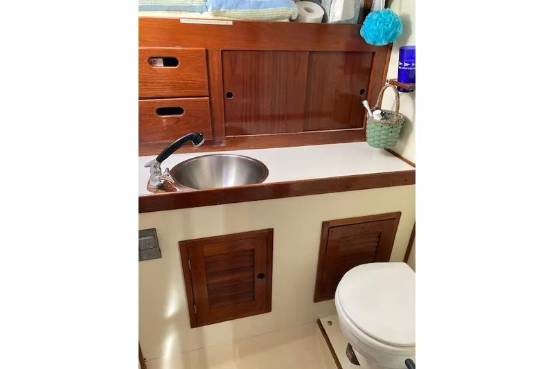 Slide: The Image of 1975 Tartan 41 yacht bathroom with wooden cabinets, sink, and toilet. - 17