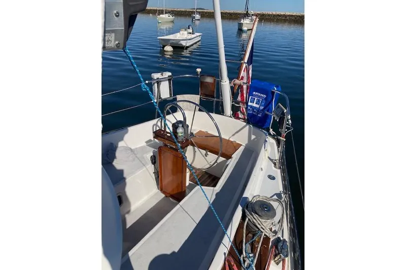 Slide: The Image of 1975 Tartan 41 sailboat cockpit with steering wheel, moored in calm waters. - 4