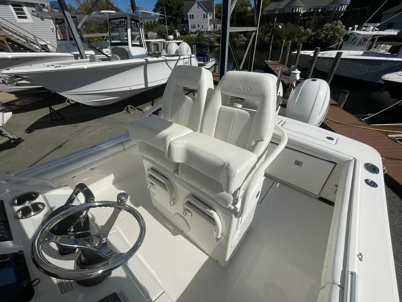 Slide: The Image of 2019 Regulator 23 boat interior with white seating and steering wheel. - 13