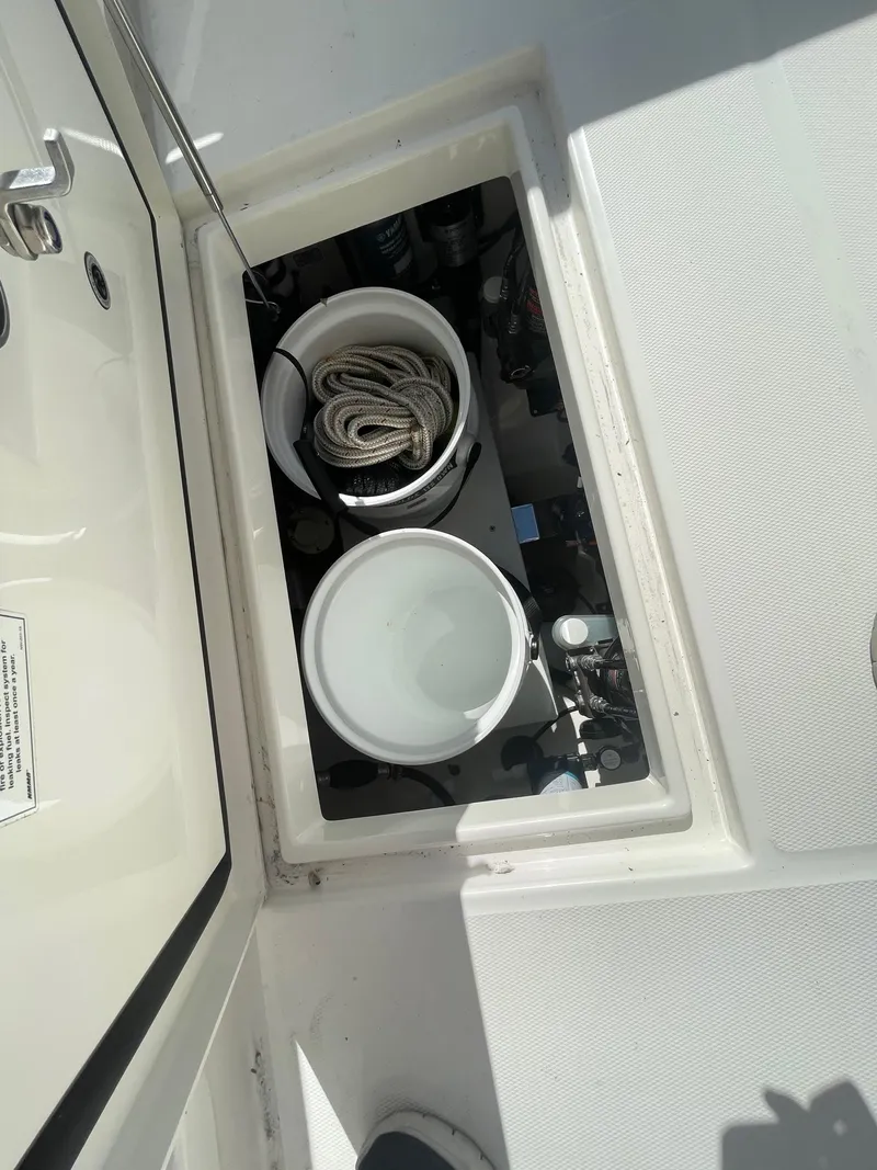 Slide: The Image of Storage compartment on a 2019 Regulator 23 boat with buckets and rope. - 16