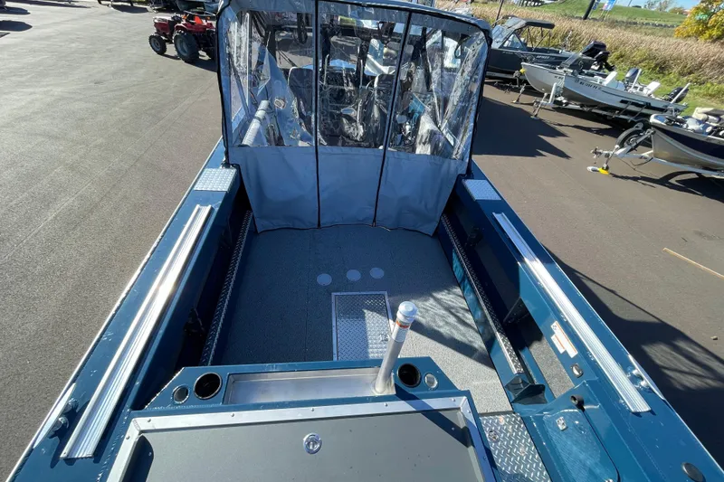 Slide: The Image of 2026 Hewescraft 210 Sea Runner ET boat interior with protective cover, parked outdoors. - 6