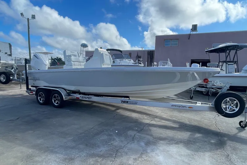 The Image of 2026 Pathfinder 2500 Hybrid boat on trailer, parked outdoors under a cloudy sky. - 1