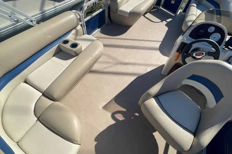 Slide: The Image of 2013 Sun Tracker Party Barge 18 DLX interior with beige seating and steering console. - 11