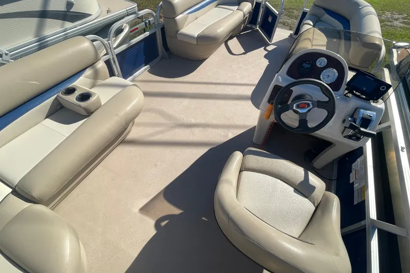 Slide: The Image of 2013 Sun Tracker Party Barge 18 DLX interior with beige seating and steering console. - 7