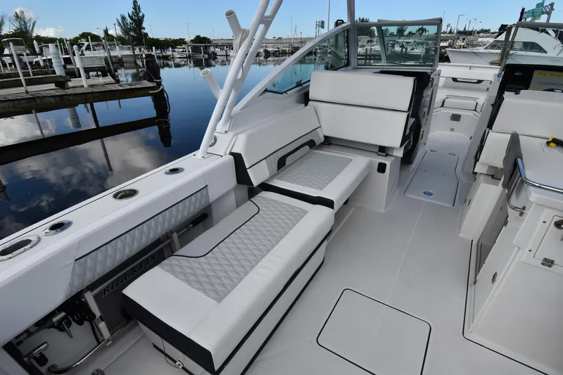 Slide: The Image of 2022 Blackfin 272DC boat interior with white seating and sleek design at a marina. - 10