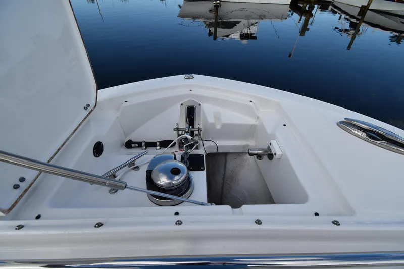 Slide: The Image of 2022 Blackfin 272DC boat anchor compartment with winch, docked on calm water. - 15