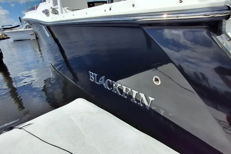 Slide: The Image of 2023 Blackfin 272DC boat docked, showcasing sleek design and reflective hull. - 20
