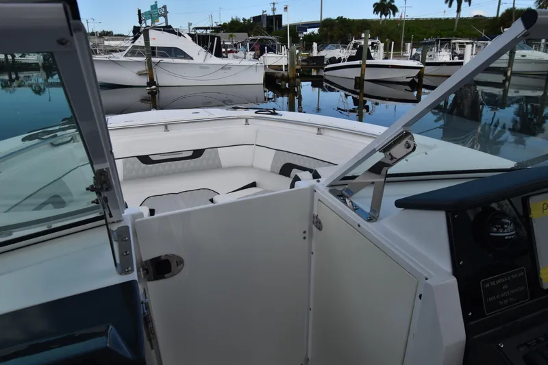 Slide: The Image of 2022 Blackfin 272DC boat interior at marina, showcasing seating and open hatch. - 23