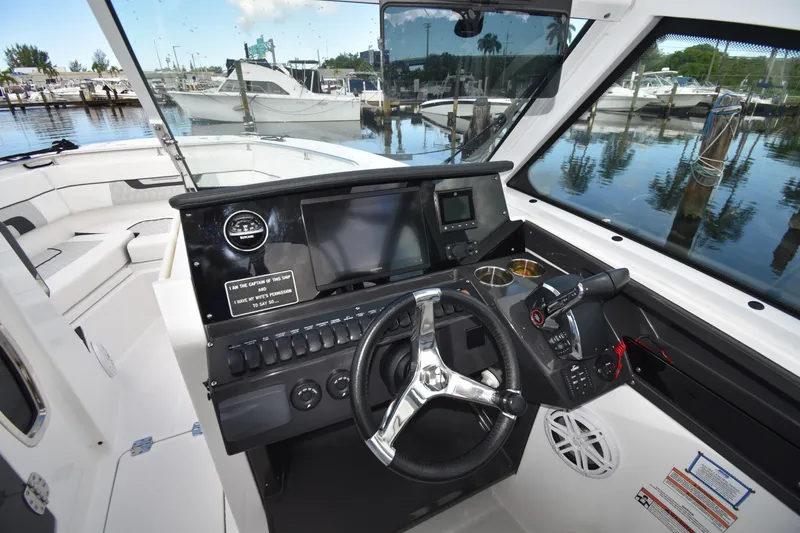 Slide: The Image of 2022 Blackfin 272DC boat cockpit with modern controls and marina view. - 26