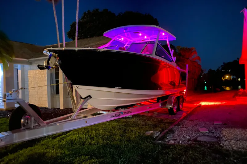 Slide: The Image of 2022 Blackfin 272DC boat on trailer, illuminated with vibrant red and purple lights at night. - 4