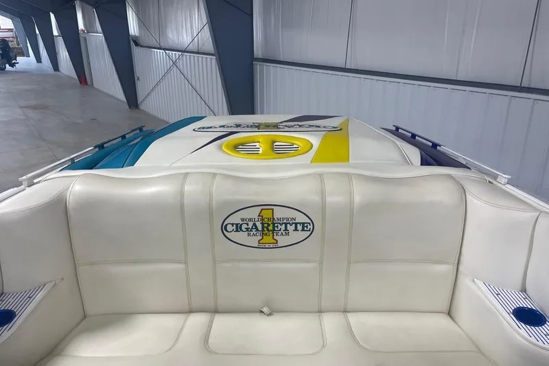 Slide: The Image of 2002 Cigarette 38 Top Gun boat interior with logo, featuring white seating in a storage facility. - 10
