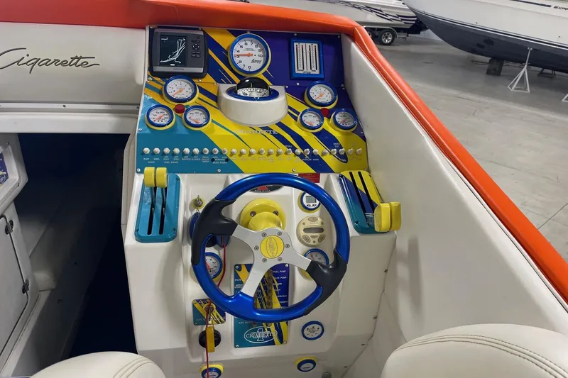 Slide: The Image of 2002 Cigarette 38 Top Gun boat dashboard with colorful gauges and steering wheel. - 30