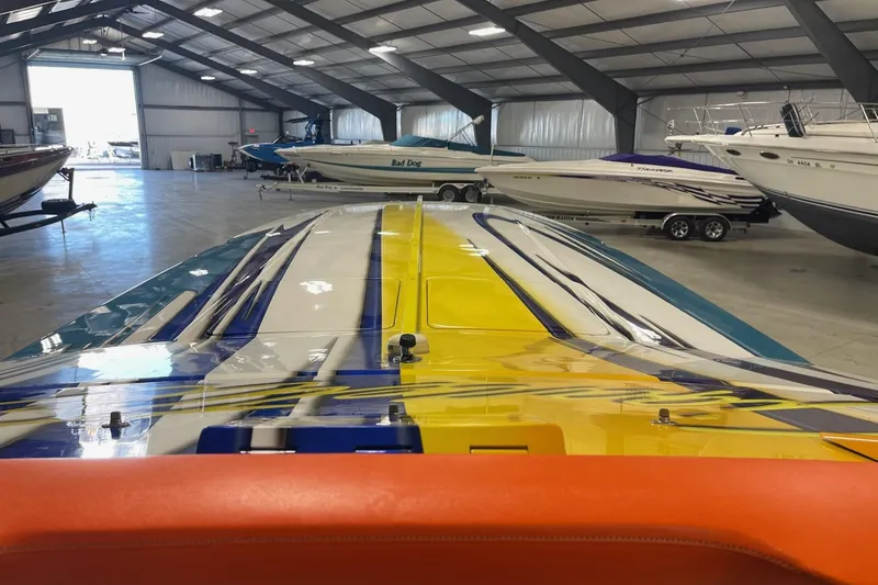 Slide: The Image of 2002 Cigarette 38 Top Gun boat with vibrant design in a spacious indoor storage facility. - 39