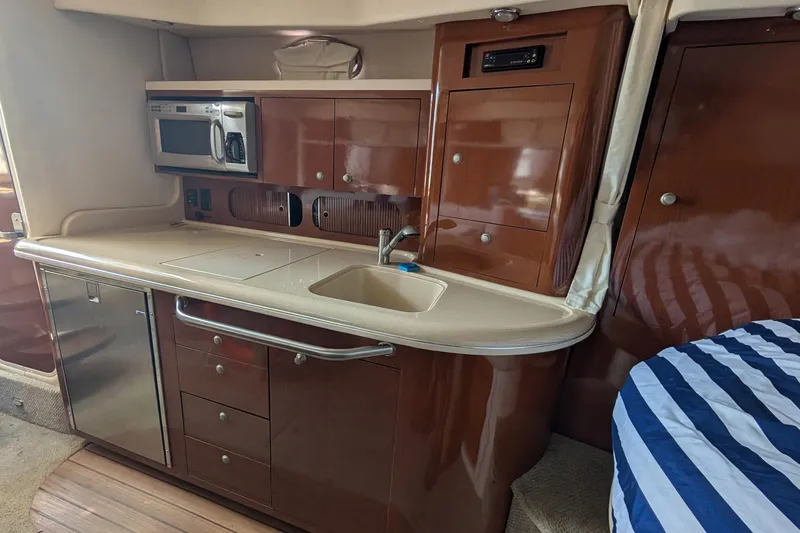 Slide: The Image of 2008 Sea Ray 340 Sundancer interior kitchen with microwave, sink, and wooden cabinetry. - 12
