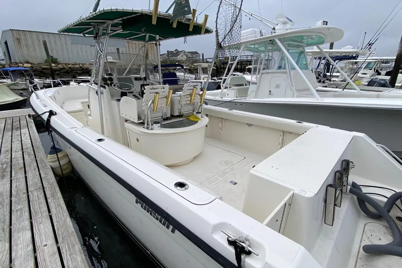 Slide: The Image of 2005 Pursuit 2870 Center Console boat docked, featuring spacious deck and seating. - 6
