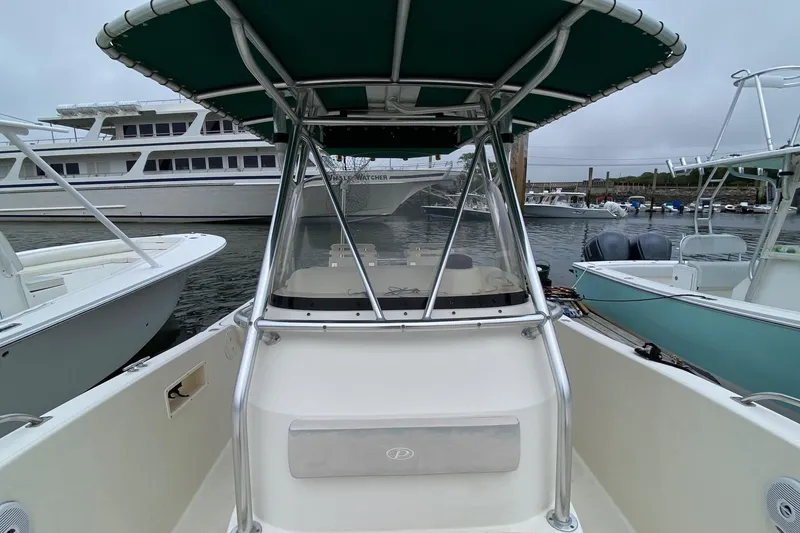 Slide: The Image of 2005 Pursuit 2870 Center Console boat docked, featuring a green canopy and spacious deck. - 9