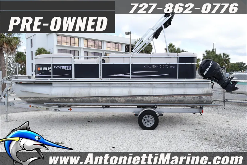 Slide: The Image of Pre-owned 2012 Harris FloteBote Cruiser CX 200 pontoon boat on trailer, displayed outdoors. - 3