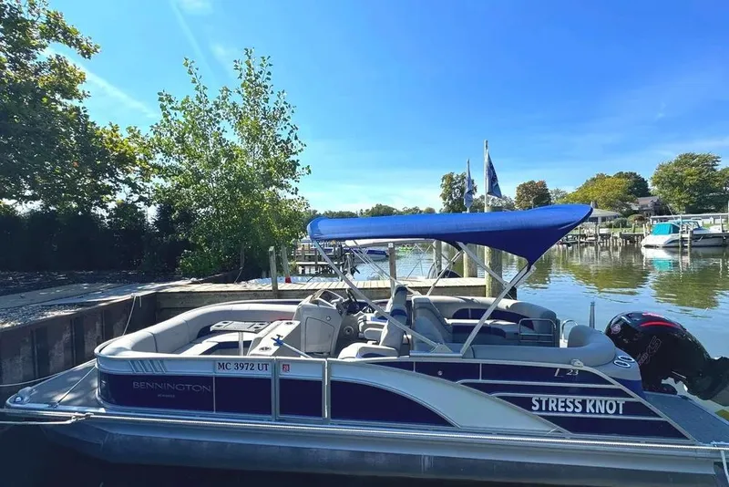 Slide: The Image of 2022 Bennington 23 LTFB pontoon boat docked by a scenic riverside. - 2