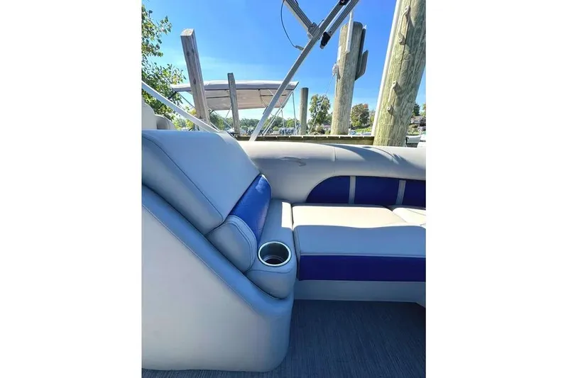 Slide: The Image of 2022 Bennington 23 LTFB boat interior with blue and gray seating, cup holder, and sunny dock view. - 23