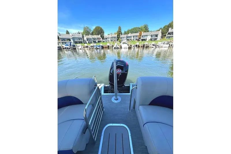 Slide: The Image of 2022 Bennington 23 LTFB pontoon boat on a serene waterfront with docked boats. - 26