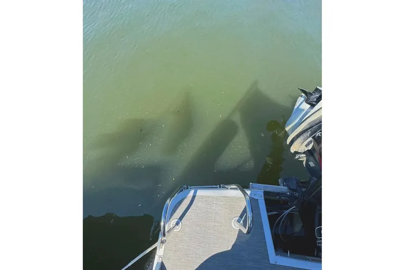 Slide: The Image of 2022 Bennington 23 LTFB pontoon boat with motor, casting shadow on water. - 28