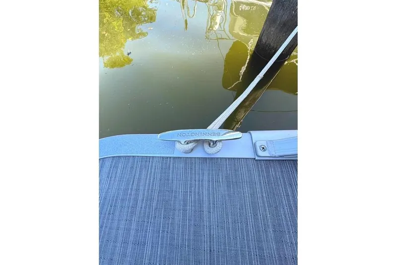 Slide: The Image of 2022 Bennington 23 LTFB boat cleat with rope, docked on calm water. - 30