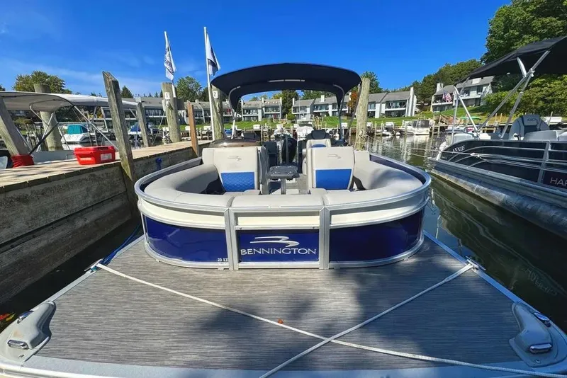 Slide: The Image of 2022 Bennington 23 LTFB pontoon boat docked at a marina under clear blue skies. - 33