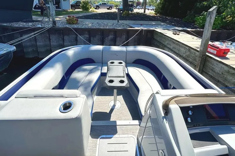 Slide: The Image of 2022 Bennington 23 LTFB pontoon boat interior with seating and table, docked at marina. - 5