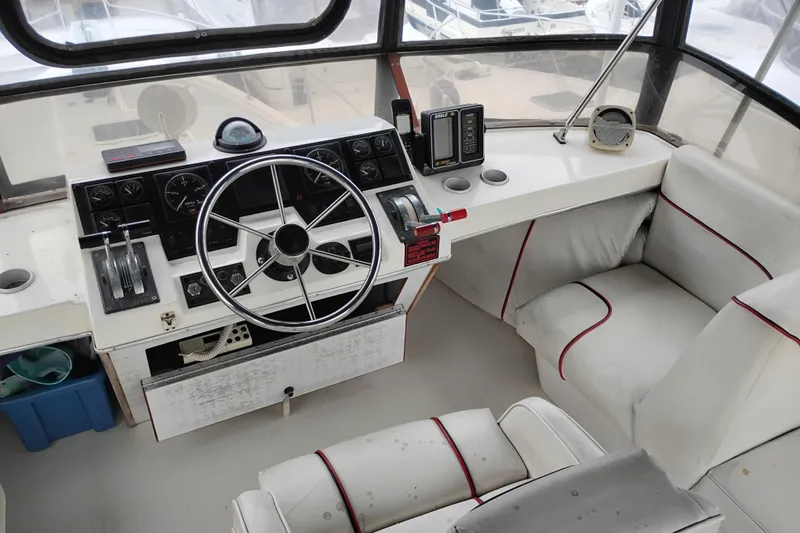 Slide: The Image of 1990 Bayliner 3888 Motoryacht helm with steering wheel, gauges, and white seating. - 10