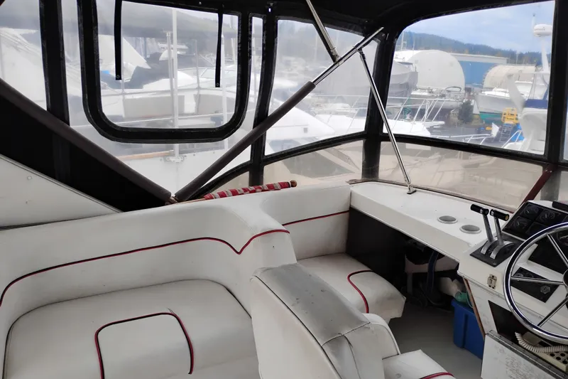 Slide: The Image of 1990 Bayliner 3888 Motoryacht cockpit with steering wheel and seating, docked at marina. - 11