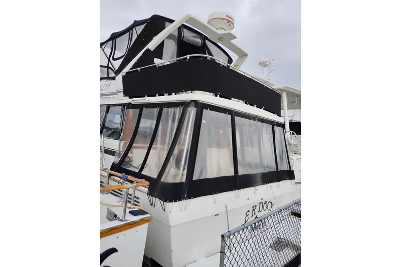 Slide: The Image of 1990 Bayliner 3888 Motoryacht with black canvas enclosure at dock. - 2