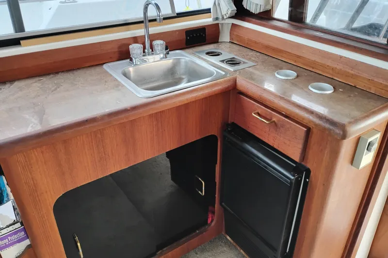Slide: The Image of 1990 Bayliner 3888 Motoryacht kitchen with sink, stove, and wooden cabinetry. - 20