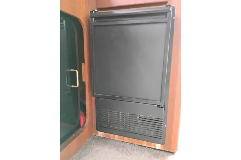 Slide: The Image of 1990 Bayliner 3888 Motoryacht interior fridge, black panel, wooden cabinetry. - 21