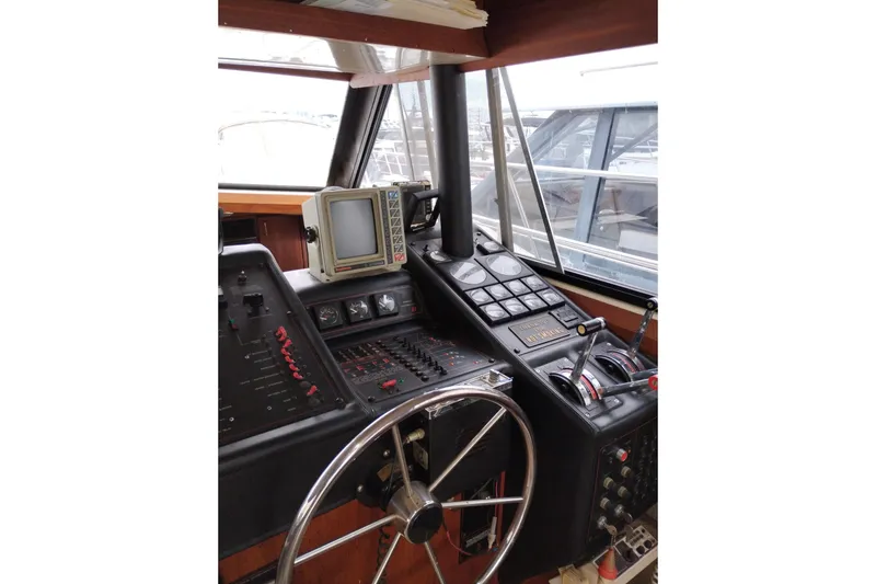Slide: The Image of 1990 Bayliner 3888 Motoryacht helm with steering wheel and navigation controls. - 25