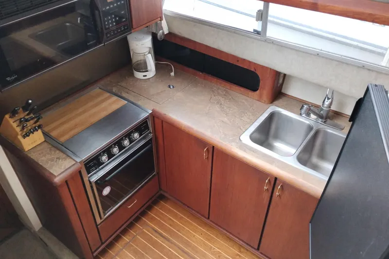Slide: The Image of 1990 Bayliner 3888 Motoryacht kitchen with stove, sink, and wooden cabinetry. - 27