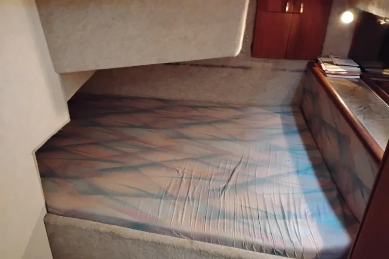 Slide: The Image of 1990 Bayliner 3888 Motoryacht cabin interior with patterned bed and wooden accents. - 34