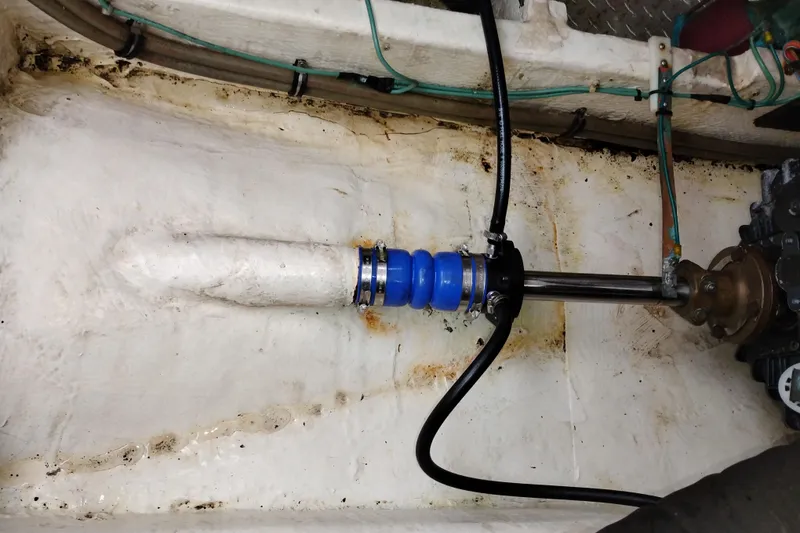 Slide: The Image of 1990 Bayliner 3888 Motoryacht engine compartment with visible shaft and hoses. - 49