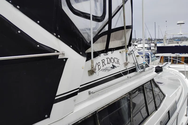 Slide: The Image of 1990 Bayliner 3888 Motoryacht docked, featuring black and white exterior details. - 52