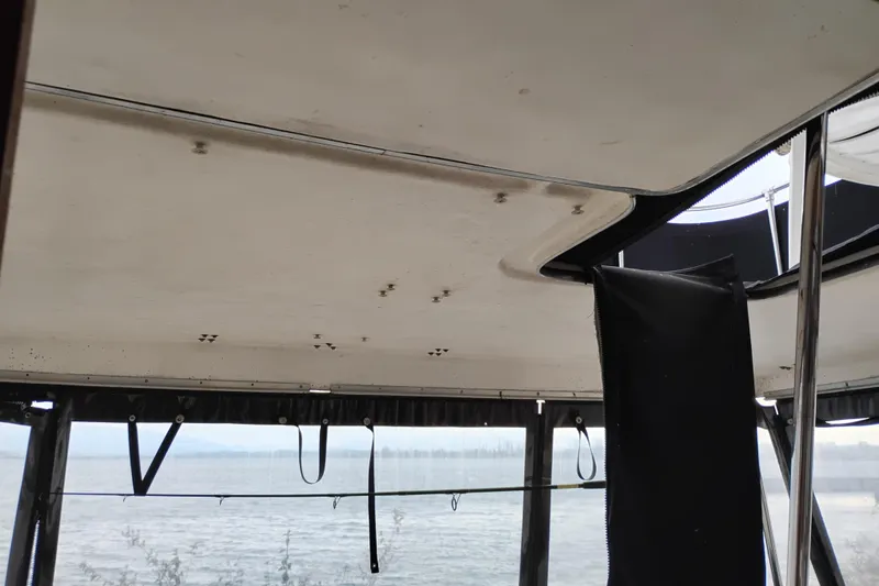 Slide: The Image of 1990 Bayliner 3888 Motoryacht interior ceiling with visible wear, overlooking water. - 6
