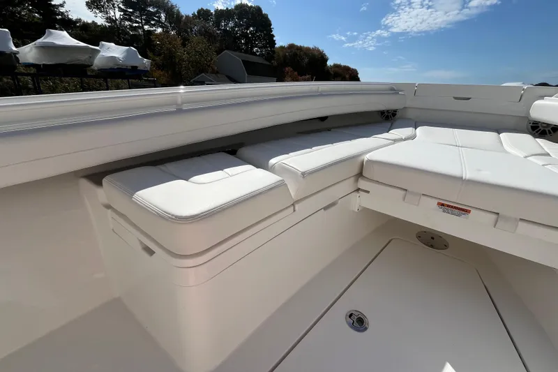 Slide: The Image of 2023 Regulator 28 boat interior with white cushioned seating under a clear blue sky. - 13