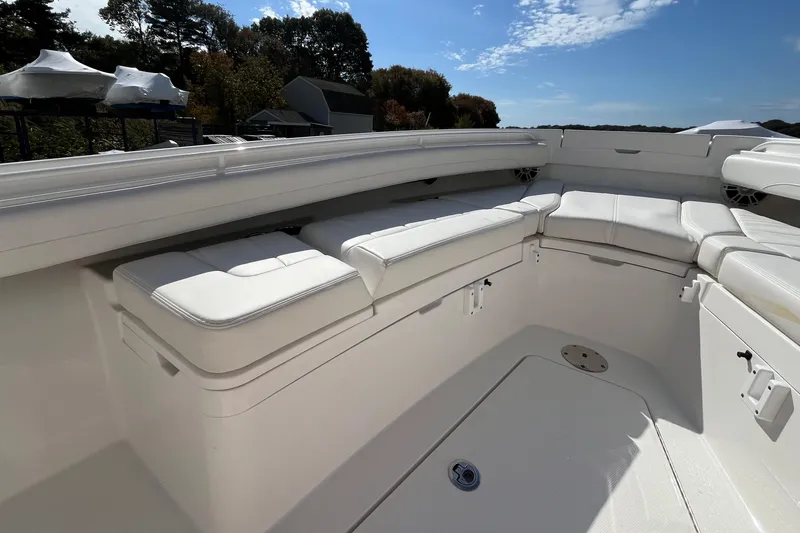 Slide: The Image of 2023 Regulator 28 boat interior with white cushioned seating under a clear blue sky. - 18