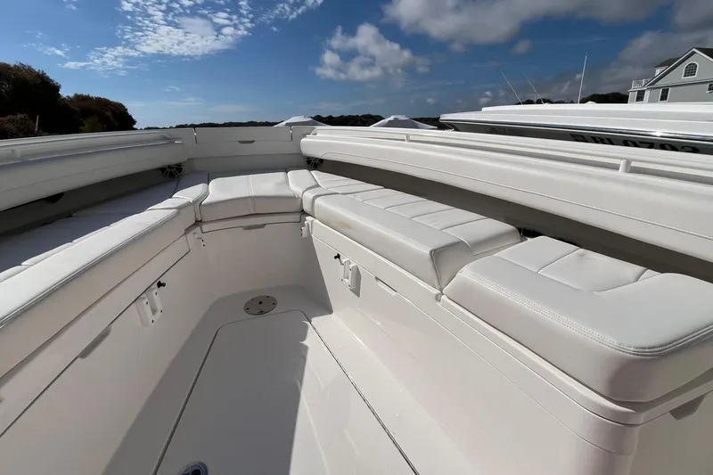 Slide: The Image of 2023 Regulator 28 boat interior with white cushioned seating under a blue sky. - 19