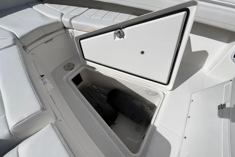 Slide: The Image of 2023 Regulator 28 boat storage compartment with open hatch and cushioned seating. - 21