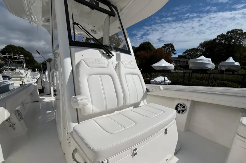 Slide: The Image of 2023 Regulator 28 boat interior with white seating and console, under a partly cloudy sky. - 23