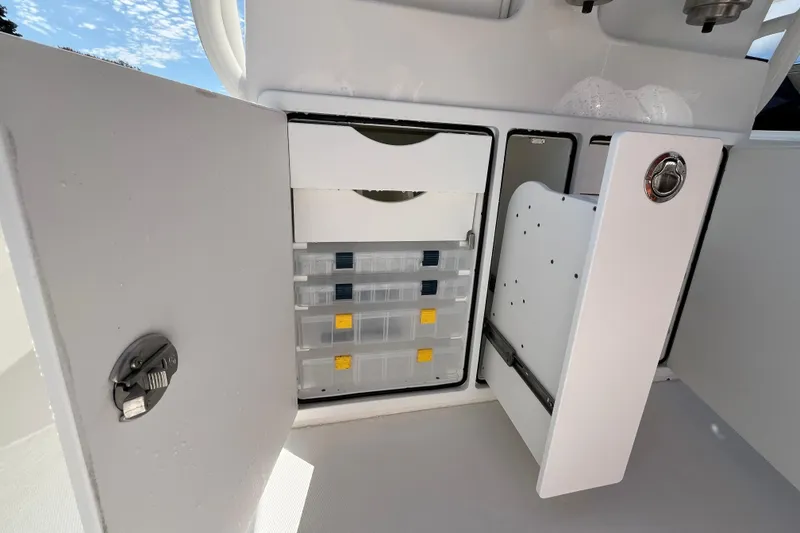 Slide: The Image of Storage compartment on a 2023 Regulator 28 boat, featuring organized tackle boxes. - 44