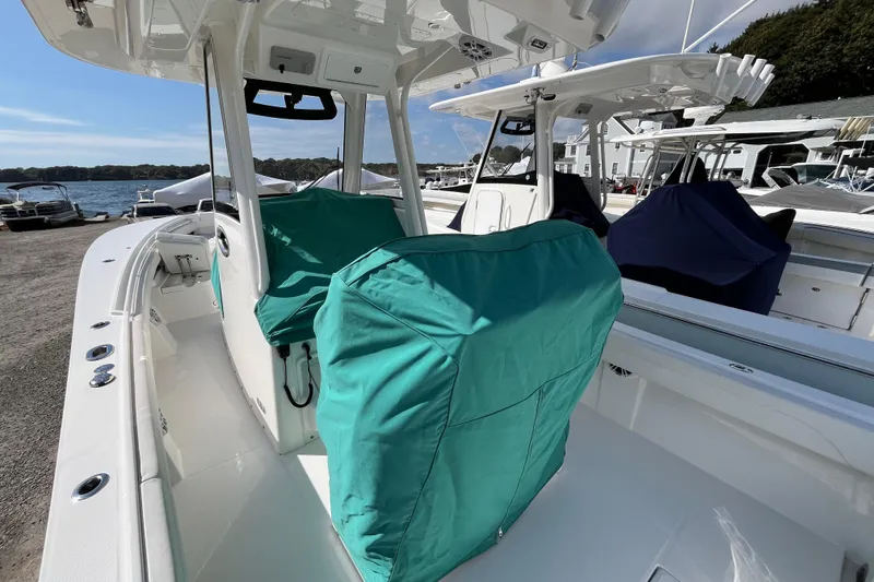 Slide: The Image of 2023 Regulator 28 boat with covered seats, docked near a marina under clear skies. - 53